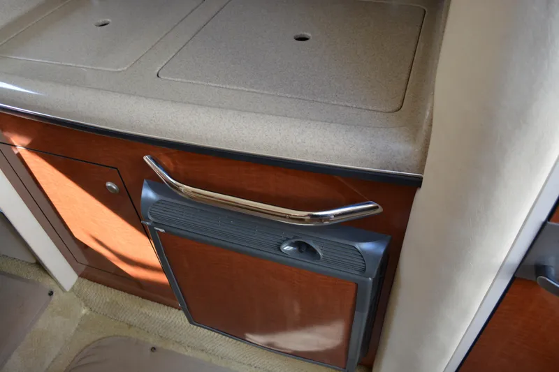 Slide: The Image of Interior of 2005 Sea Ray 280 Sundancer showing kitchenette with wood finish and compact fridge. - 17