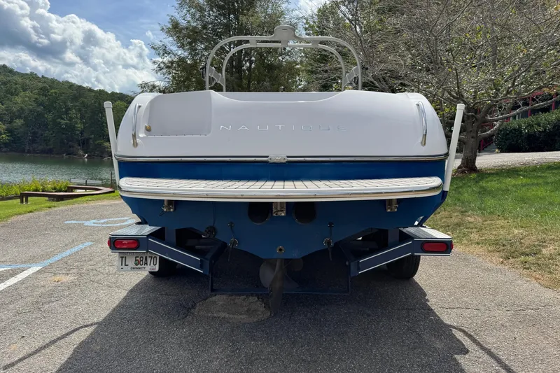 Slide: The Image of 2004 Correct Craft Air Nautique 226 boat on trailer by a lake. - 3