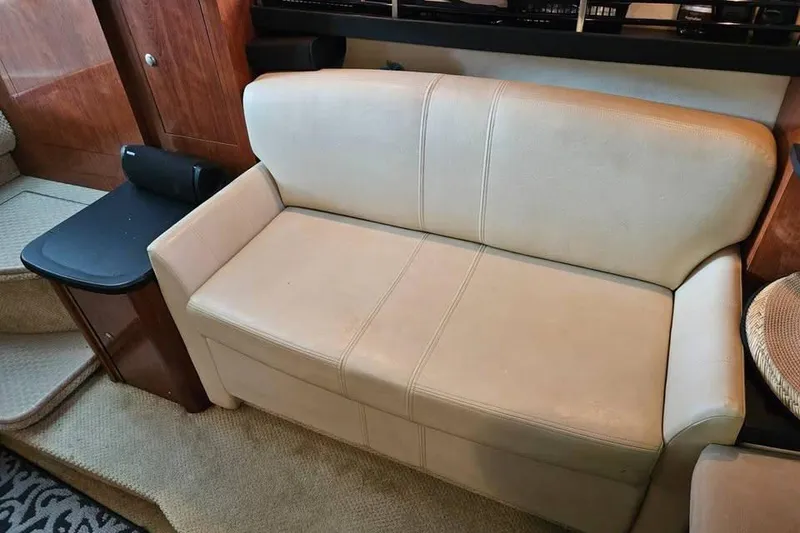 Slide: The Image of 2006 Sea Ray 290 Sundancer interior with beige leather sofa and wooden cabinetry. - 12