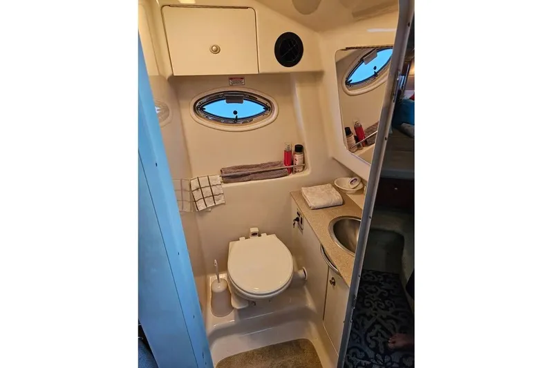 Slide: The Image of 2006 Sea Ray 290 Sundancer bathroom with toilet, sink, and porthole window. - 14