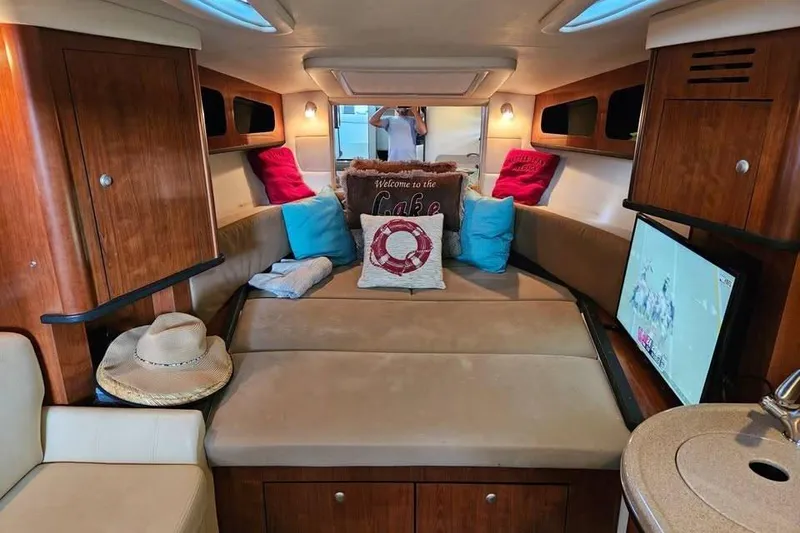 Slide: The Image of Interior of 2006 Sea Ray 290 Sundancer with cozy seating, pillows, and a TV. - 9