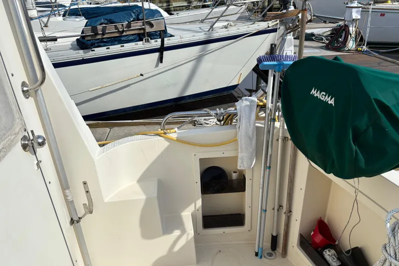Slide: The Image of 2004 Camano Trawler deck with cleaning tools and covered equipment, docked near other boats. - 10