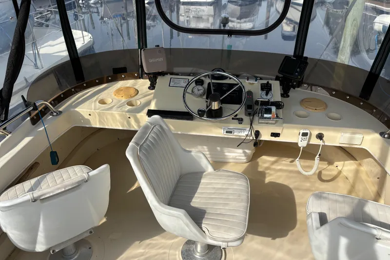 Slide: The Image of 2004 Camano Trawler helm with steering wheel, navigation equipment, and white captain chairs. - 11