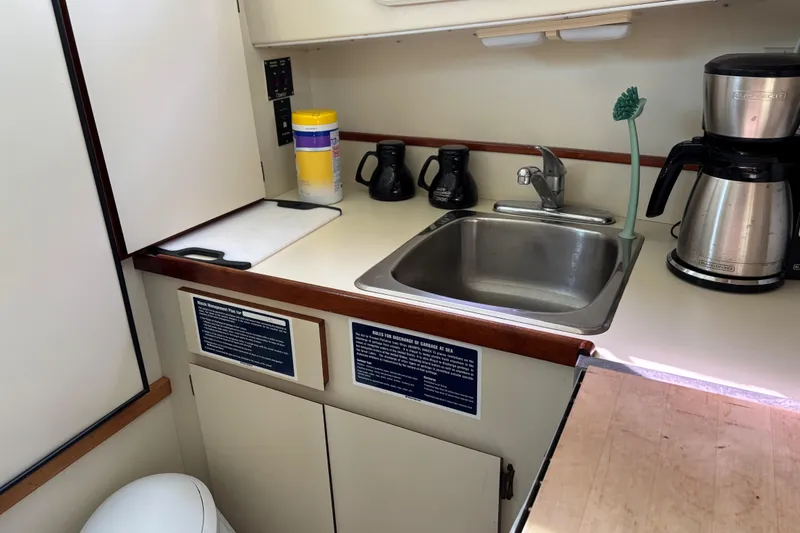 Slide: The Image of 2004 Camano Trawler kitchen with sink, coffee maker, and cleaning supplies. - 15