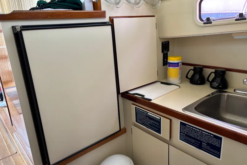 Slide: The Image of 2004 Camano Trawler kitchen with fridge, sink, and countertop essentials. - 16