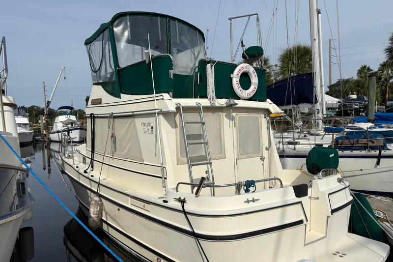 Slide: The Image of 2004 Camano Trawler docked at marina, featuring green canopy and life preserver. - 5