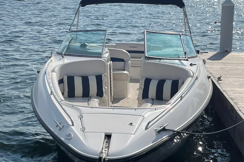 Slide: The Image of 1999 Chaparral 2830 SS boat docked on water, featuring open seating and striped cushions. - 2