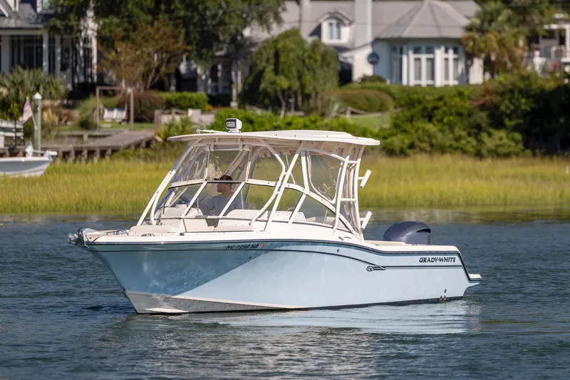 Slide: The Image of 2017 Grady-White Freedom 235 boat cruising on a scenic waterway near houses. - 14