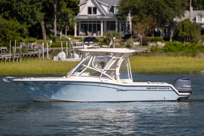 Slide: The Image of 2017 Grady-White Freedom 235 boat cruising on a serene lake near a residential area. - 15