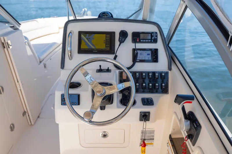 Slide: The Image of 2017 Grady-White Freedom 235 boat helm with steering wheel and navigation controls. - 19