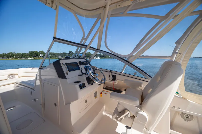 Slide: The Image of 2017 Grady-White Freedom 235 boat interior with steering wheel and seating, on calm water. - 22