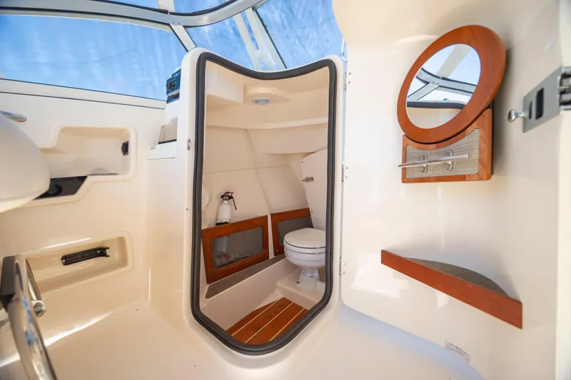 Slide: The Image of 2017 Grady-White Freedom 235 boat interior with compact bathroom and wooden accents. - 24