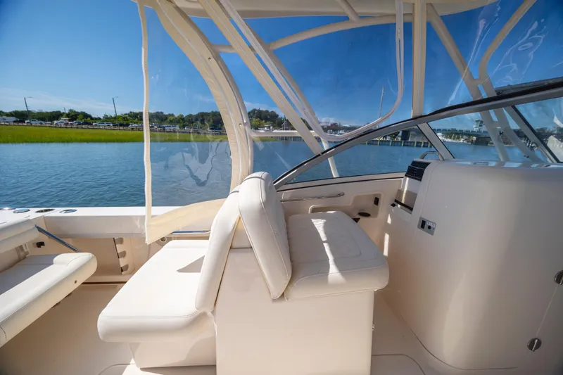 Slide: The Image of 2017 Grady-White Freedom 235 boat interior with seating and clear canopy on a sunny day. - 27