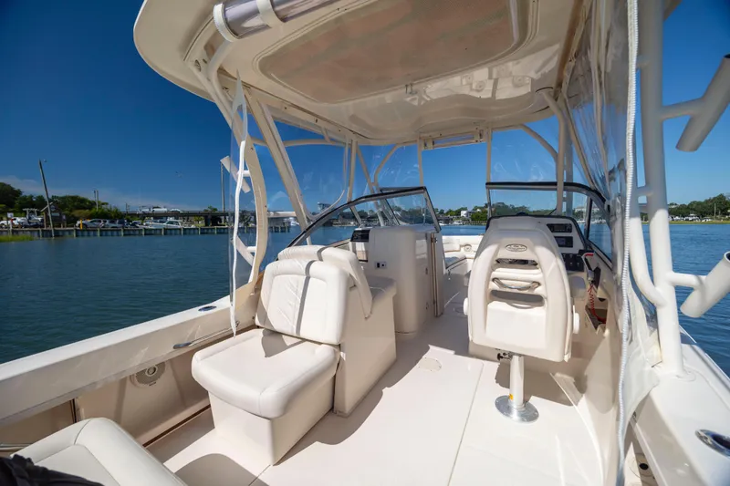 Slide: The Image of 2017 Grady-White Freedom 235 boat interior with seating and helm, docked by calm waters. - 29