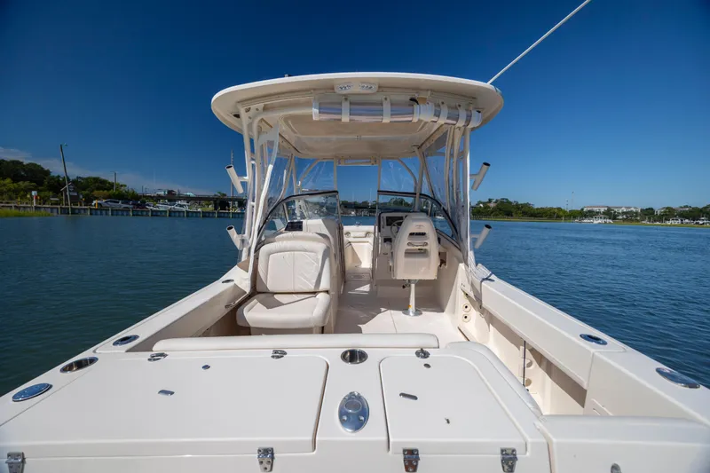 Slide: The Image of 2017 Grady-White Freedom 235 boat on calm water, showcasing spacious deck and seating. - 30