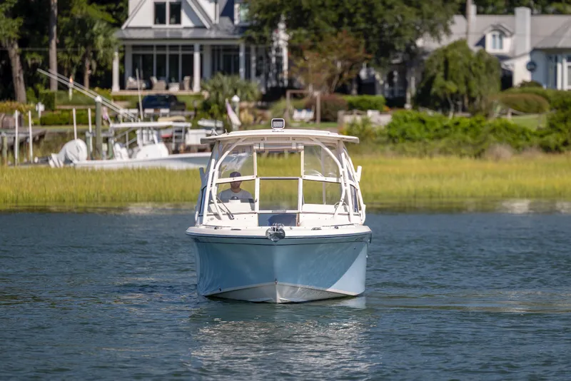 Slide: The Image of 2017 Grady-White Freedom 235 boat cruising on a calm lake near waterfront homes. - 4