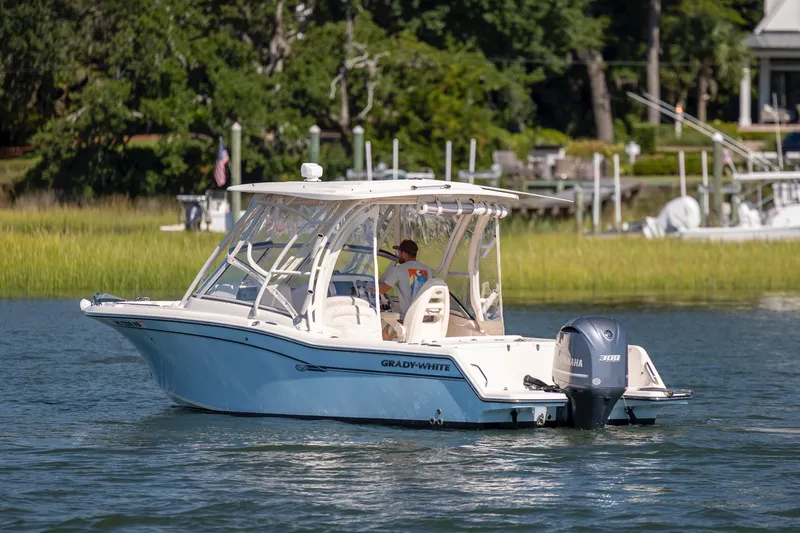 Slide: The Image of 2017 Grady-White Freedom 235 boat cruising on a serene lake with lush greenery. - 7