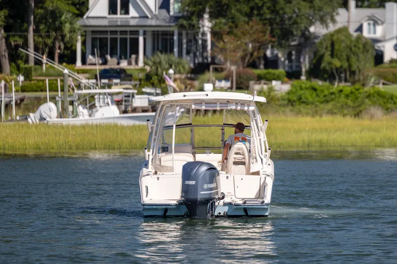 Slide: The Image of 2017 Grady-White Freedom 235 boat cruising on a serene waterway near waterfront homes. - 8