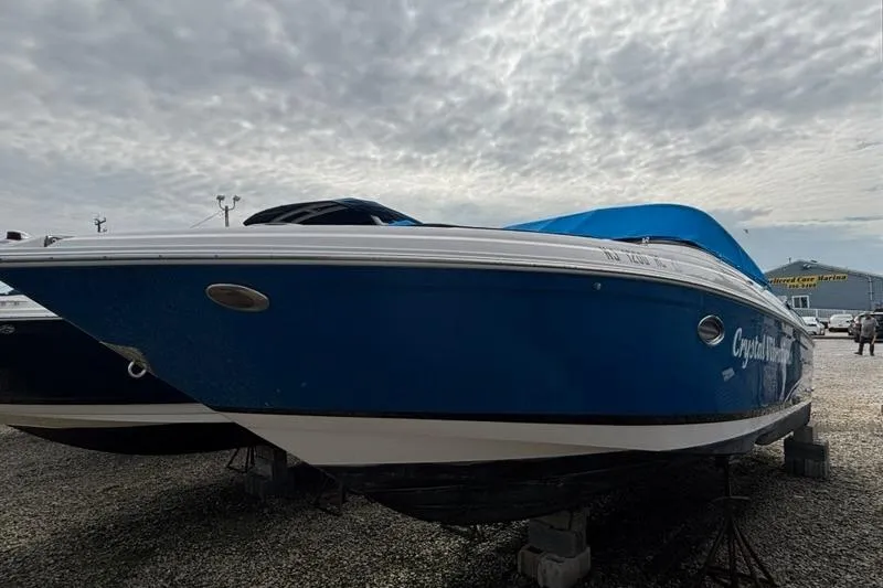 Slide: The Image of 2010 Regal 2700 ES Bowrider boat with blue cover, parked on gravel. - 2