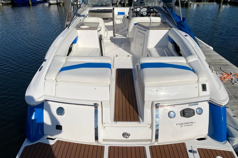 Slide: The Image of 2010 Regal 2700 ES Bowrider boat with white and blue seating, docked at marina. - 27