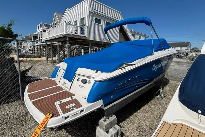 Slide: The Image of 2010 Regal 2700 ES Bowrider boat with blue hull, parked on gravel under cloudy sky. - 3