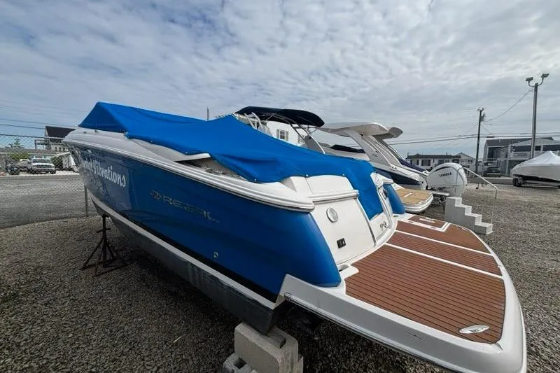 Slide: The Image of 2010 Regal 2700 ES Bowrider with blue cover and wooden deck at dock. - 7