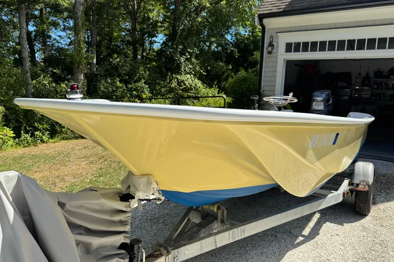 Slide: The Image of 1978 Boston Whaler Currituck boat on trailer, parked near a garage, surrounded by greenery. - 2