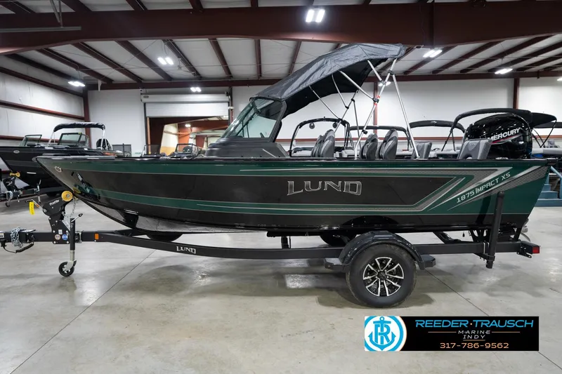 Slide: The Image of 2026 Lund 1875 Impact XS boat in showroom, featuring sleek design and Mercury engine. - 11
