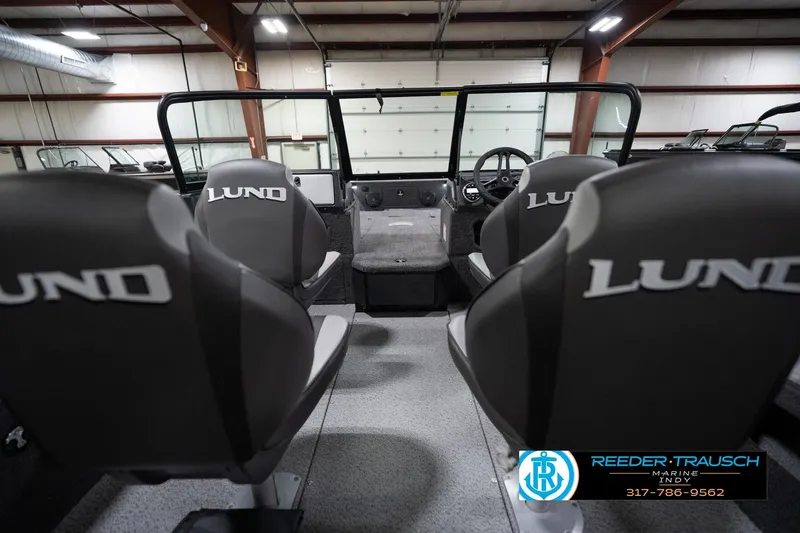 Slide: The Image of 2026 Lund 1875 Impact XS boat interior with branded seats in a showroom. - 16