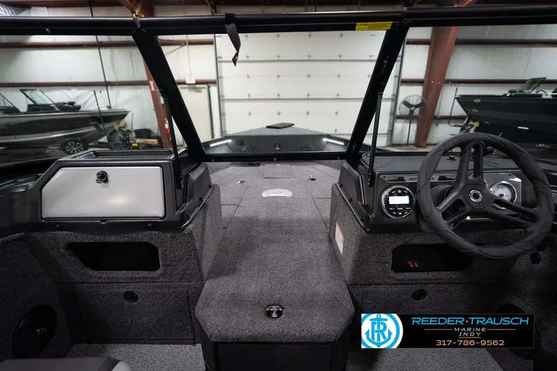 Slide: The Image of 2026 Lund 1875 Impact XS boat interior with steering wheel and dashboard in showroom. - 17