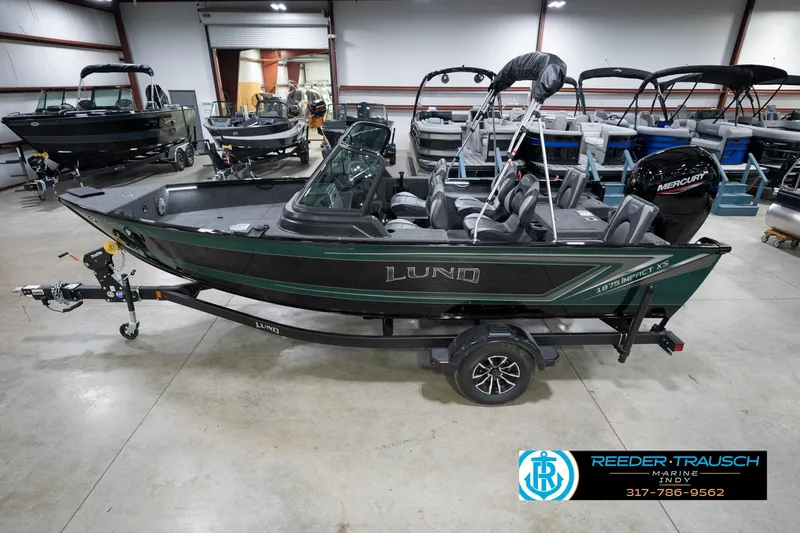 The Image of 2026 Lund 1875 Impact XS boat in showroom, featuring sleek design and Mercury engine. - 2