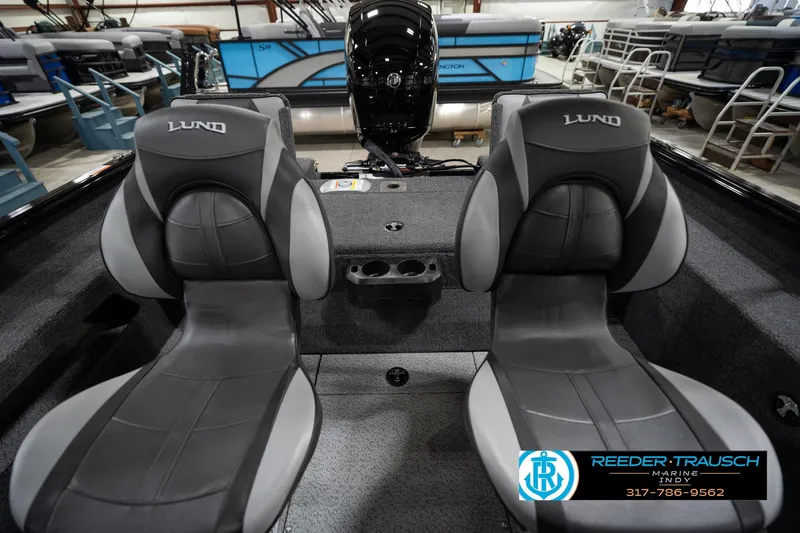 Slide: The Image of 2026 Lund 1875 Impact XS boat interior with two gray seats in a showroom. - 21