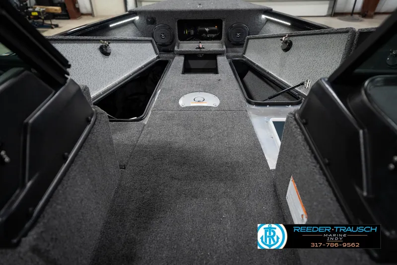 Slide: The Image of 2026 Lund 1875 Impact XS boat interior with storage compartments and carpeted flooring. - 31