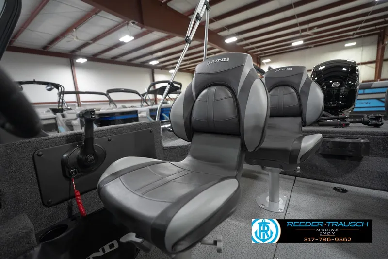 Slide: The Image of 2026 Lund 1875 Impact XS boat interior with gray seats in a showroom. - 42