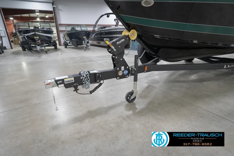 Slide: The Image of 2026 Lund 1875 Impact XS boat on trailer in showroom, Reeder Trausch Marine logo visible. - 57