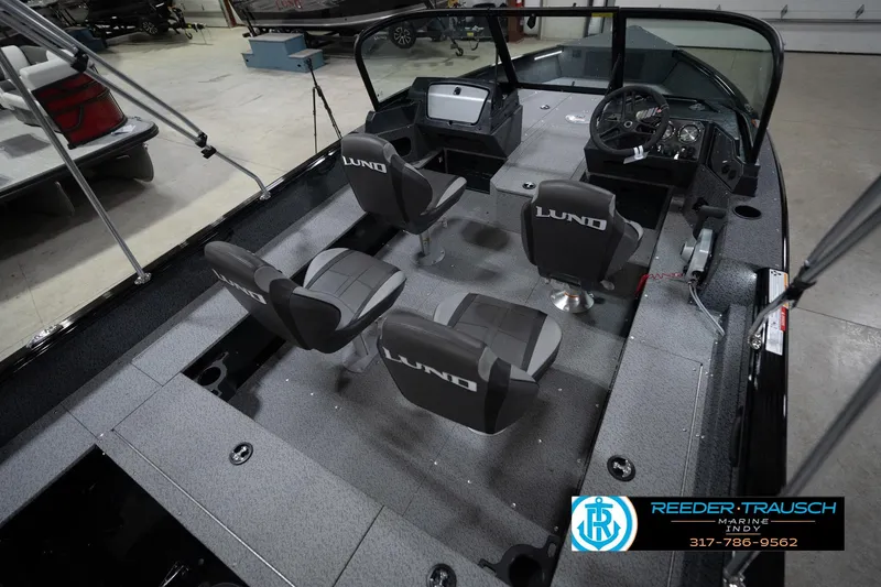 Slide: The Image of 2026 Lund 1800 Explorer Sport boat interior with seating and steering wheel, displayed indoors. - 14