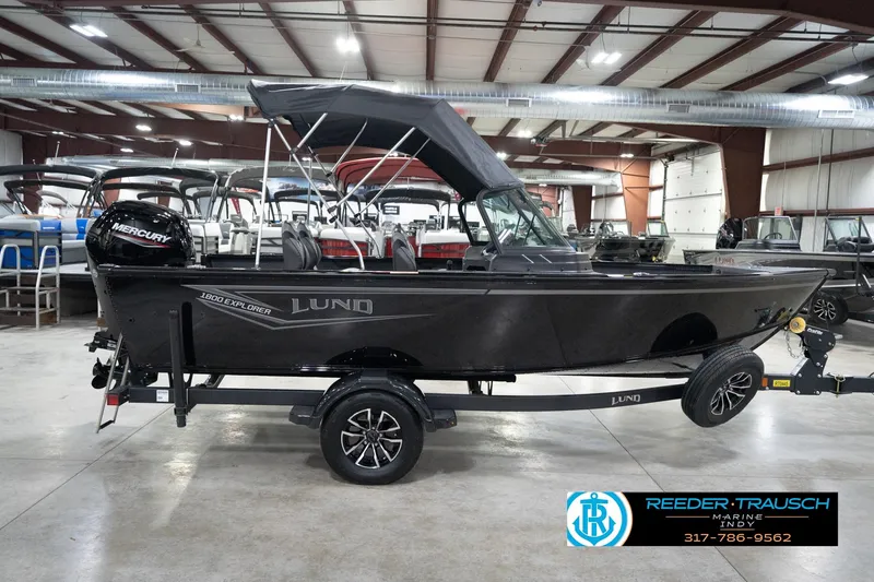 Slide: The Image of 2026 Lund 1800 Explorer Sport boat in showroom, featuring Mercury engine and trailer. - 65