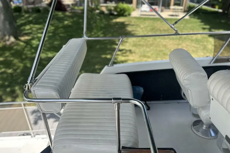 Slide: The Image of 1985 Carver 3207 Aft Cabin boat seating area with white cushioned seats and metal frame. - 4