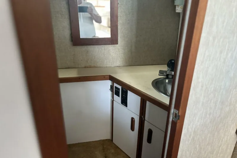 Slide: The Image of 1985 Carver 3207 Aft Cabin bathroom with sink, mirror, and storage cabinets. - 16