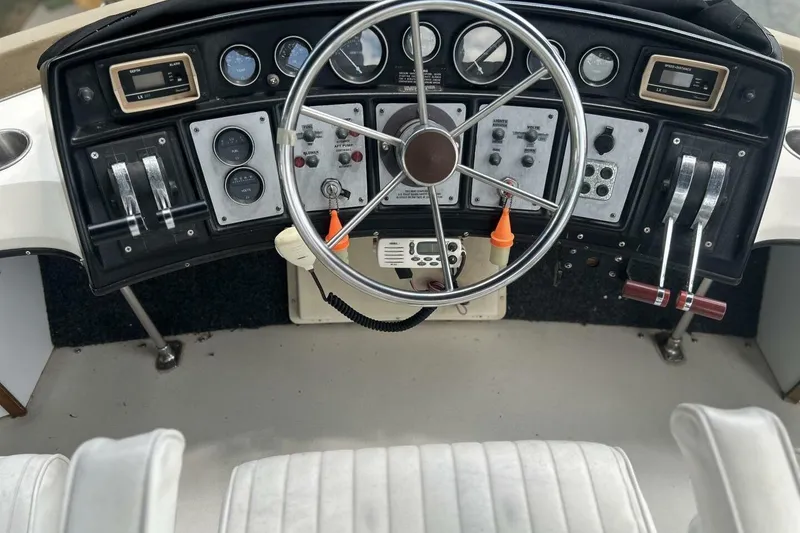 Slide: The Image of 1985 Carver 3207 Aft Cabin boat dashboard with steering wheel and control panels. - 5
