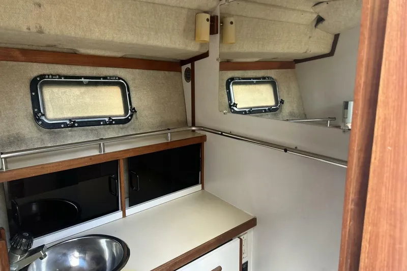 Slide: The Image of 1985 Carver 3207 Aft Cabin interior with sink, cabinets, and porthole windows. - 6