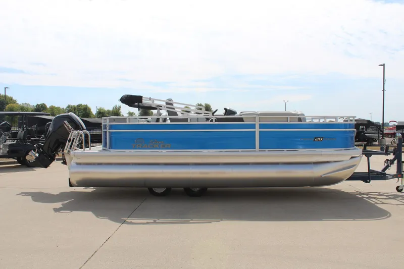 Slide: The Image of 2026 Sun Tracker Fishin' Barge 20 DLX pontoon boat, blue and silver, parked outdoors. - 4