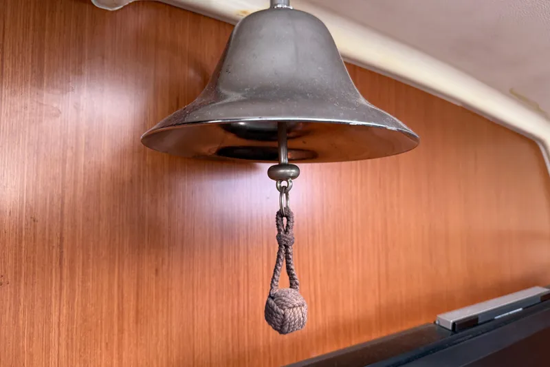 Slide: The Image of Metal bell inside 2010 Beneteau Oceanis 43 yacht, wooden interior background. - 34