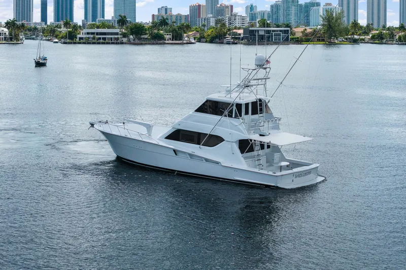 The Image of 2002 Hatteras 60 Convertible yacht cruising near city skyline. - 0