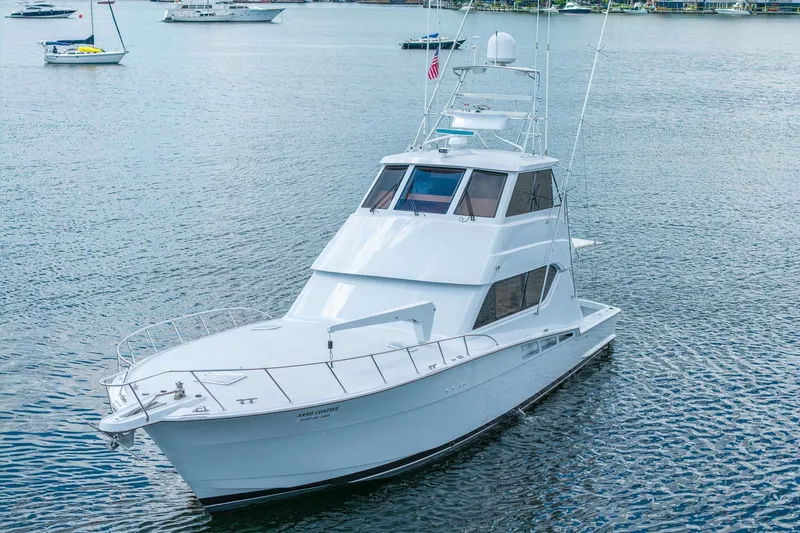 Slide: The Image of 2002 Hatteras 60 Convertible yacht on calm water, showcasing sleek design and spacious deck. - 15