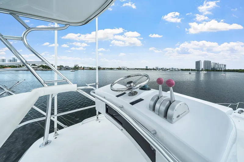 Slide: The Image of Helm of 2002 Hatteras 60 Convertible yacht overlooking calm waters and city skyline. - 53