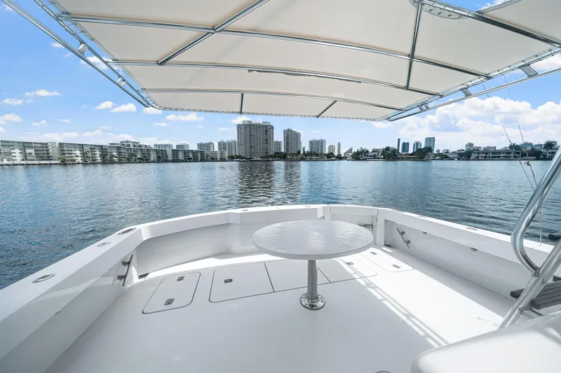 Slide: The Image of 2002 Hatteras 60 Convertible yacht deck with city skyline view, under a shaded canopy. - 59