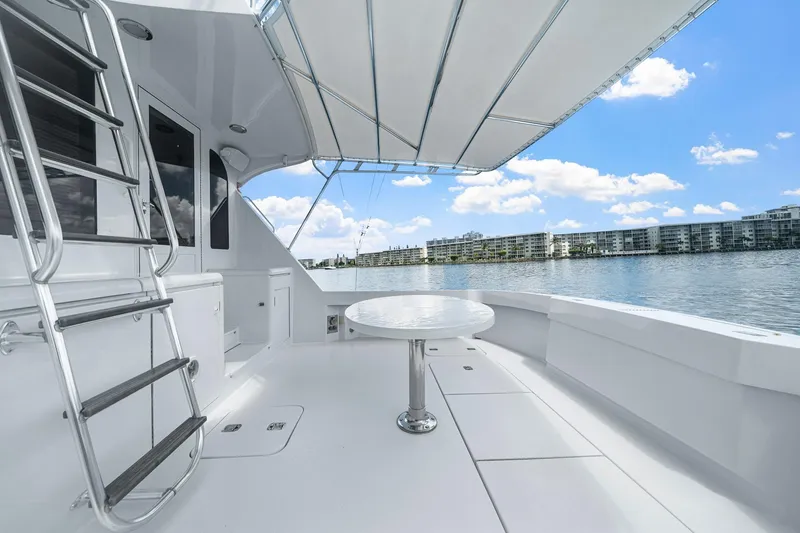 Slide: The Image of 2002 Hatteras 60 Convertible yacht deck with table, ladder, and waterfront view. - 60