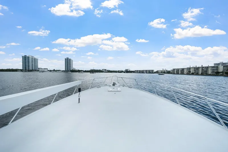 Slide: The Image of Bow view of 2002 Hatteras 60 Convertible yacht on calm waters, cityscape in background. - 64