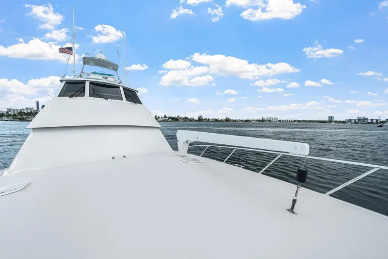 Slide: The Image of 2002 Hatteras 60 Convertible yacht cruising on a sunny day with city skyline in background. - 65
